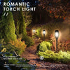 A set of warm-toned solar torch lights illuminating a garden pathway and foliage.