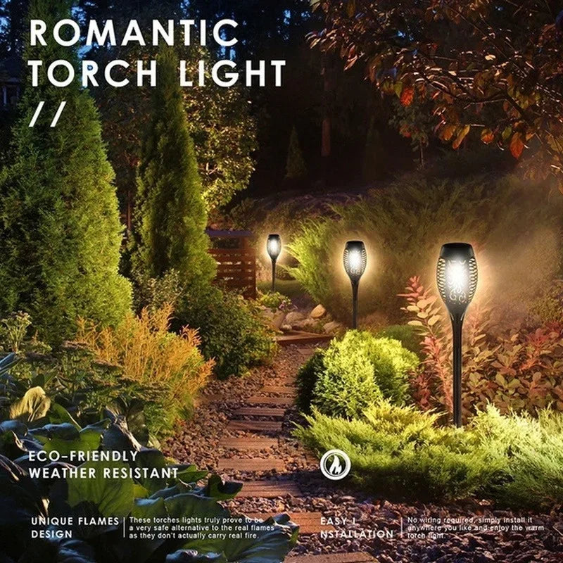 A set of warm-toned solar torch lights illuminating a garden pathway and foliage.