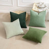 A collection of green and sage ribbed corduroy throw pillows displayed on a light beige floor.