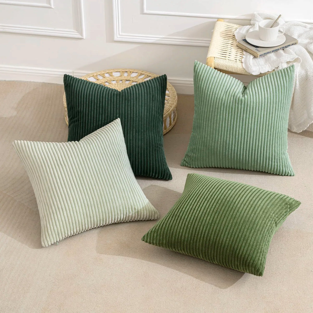 A collection of green and sage ribbed corduroy throw pillows displayed on a light beige floor.