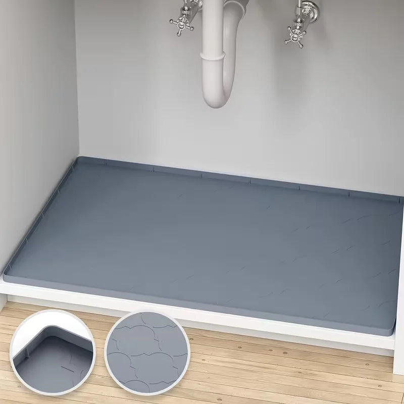 A flexible silicone sink protector mat is shown on a wooden floor next to a white cabinet, with close-ups of the mat's textur