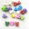 A collection of 10 mixed alphabet letter beads in various colors and shapes scattered on a white surface.