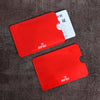 A set of red RFID blocking card sleeves and a white identification card are displayed on a dark surface.