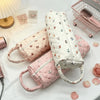 A collection of pink and white quilted cotton storage bags with handles displayed on a white surface.