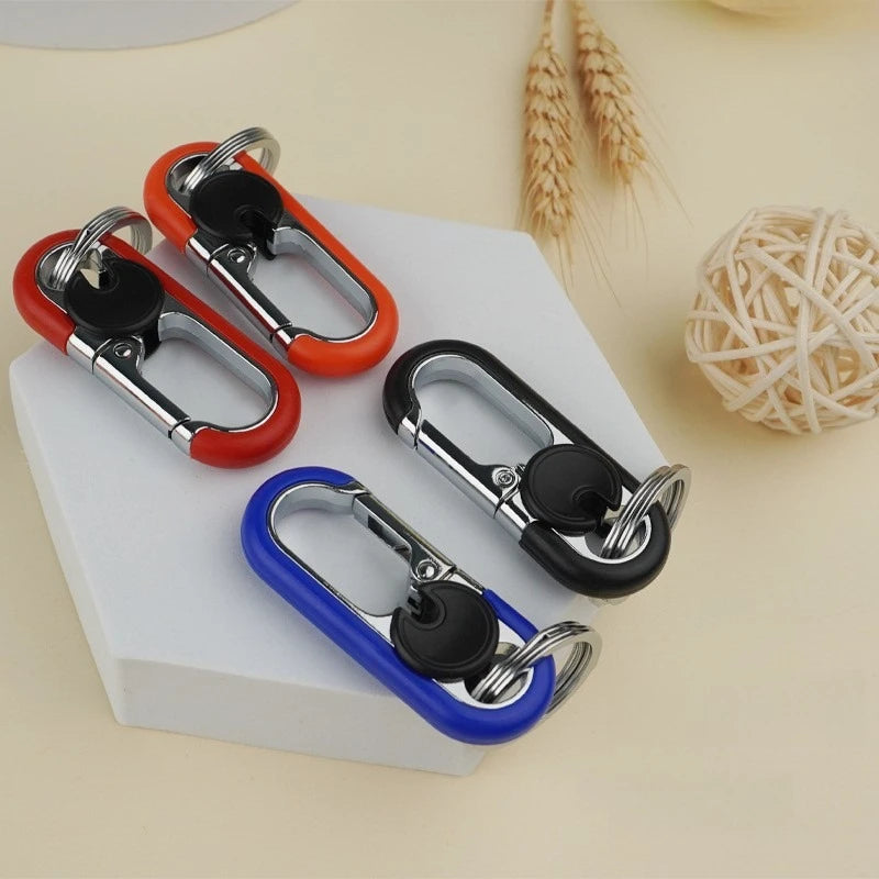 A collection of red and black carabiner lock keychains displayed on a white surface next to wheat stalks.