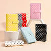 A collection of pink, yellow, red, and black polka dot PU leather binder wallets and card holders displayed on a light backgr