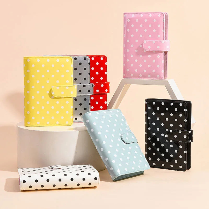 A collection of pink, yellow, red, and black polka dot PU leather binder wallets and card holders displayed on a light backgr