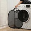 A black foldable laundry hamper is placed next to a white washing machine.