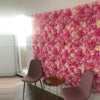 A vibrant pink silk rose flower wall panel covering a wall in an indoor setting.