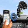 A hand holds a smartphone displaying a map, positioned near a black magnetic car phone mount.