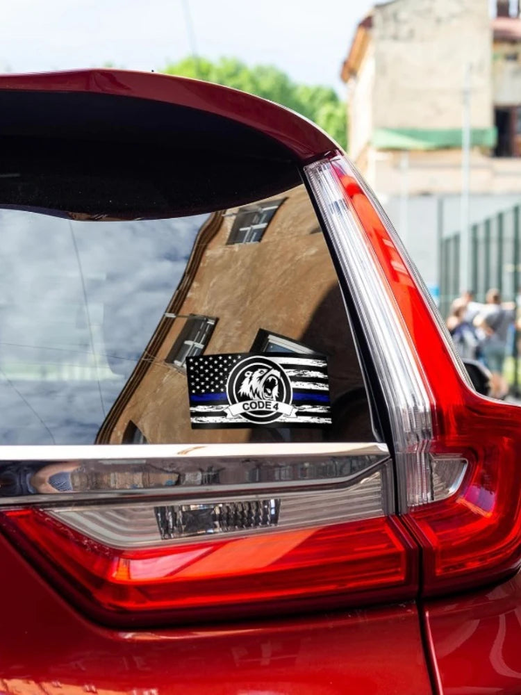Close-up of a red car's taillight showing a black and white American flag decal with the text CODE 4.
