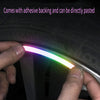 A hand is applying a glowing, multi-colored reflective rim sticker onto a tire or wheel rim.