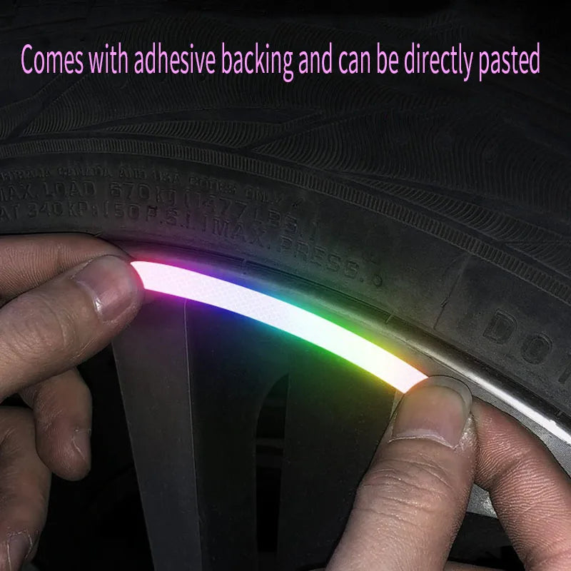 A hand is applying a glowing, multi-colored reflective rim sticker onto a tire or wheel rim.