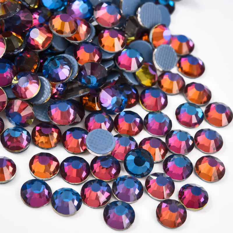 A close-up view of various iridescent and colorful hotfix rhinestones scattered on a white background.
