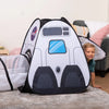 A child is smiling next to a black and white rocket ship play tent set with a tunnel and cube tent.