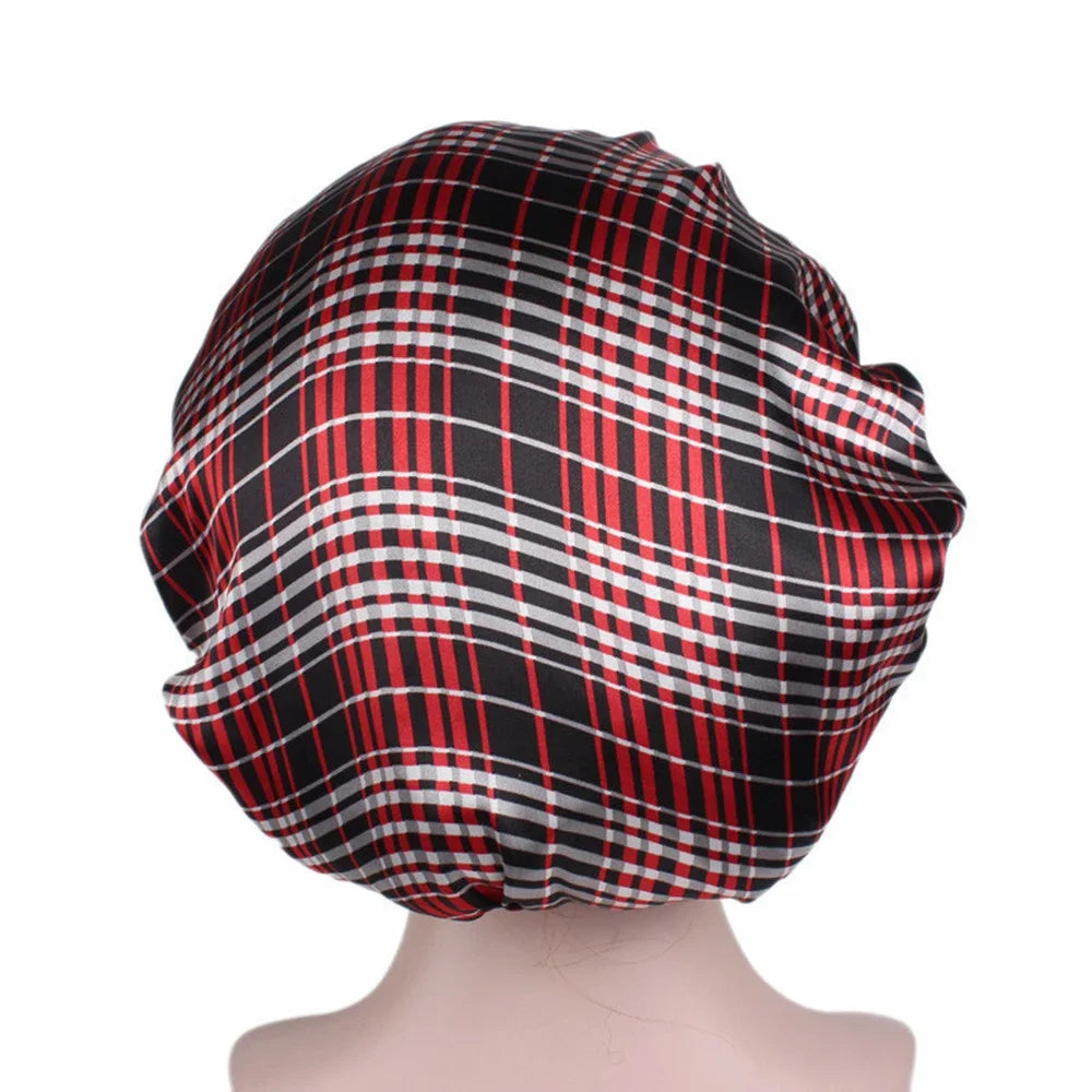 A black and red plaid satin hair bonnet displayed on a mannequin head.