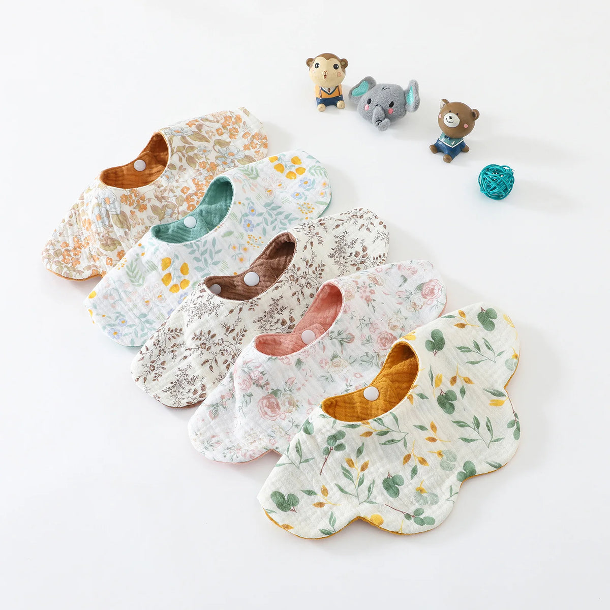 A collection of six patterned cotton baby feeding bibs and a small absorbent drool towel with animal figures.