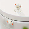 A white cartoon toilet seat lifter handle shaped like a fluffy white sheep with orange accents.