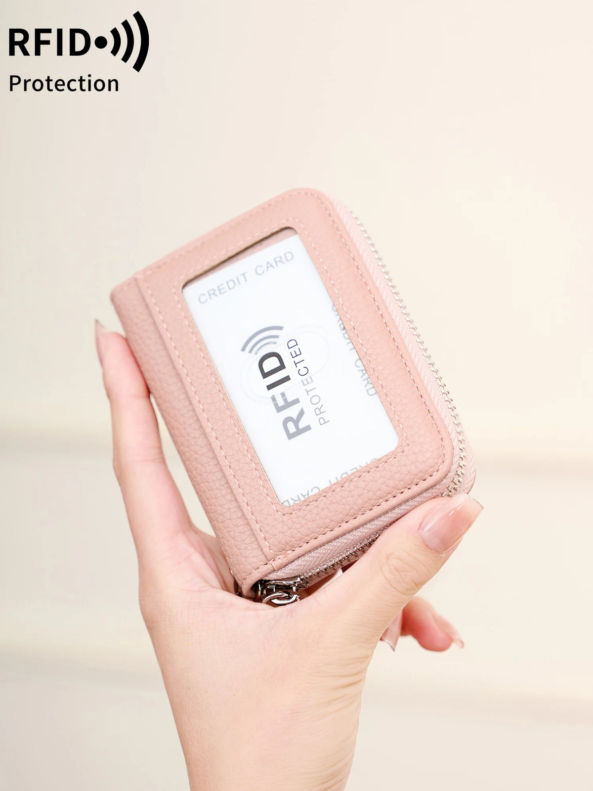 A hand holds a pink RFID protected accordion wallet designed to shield credit cards.
