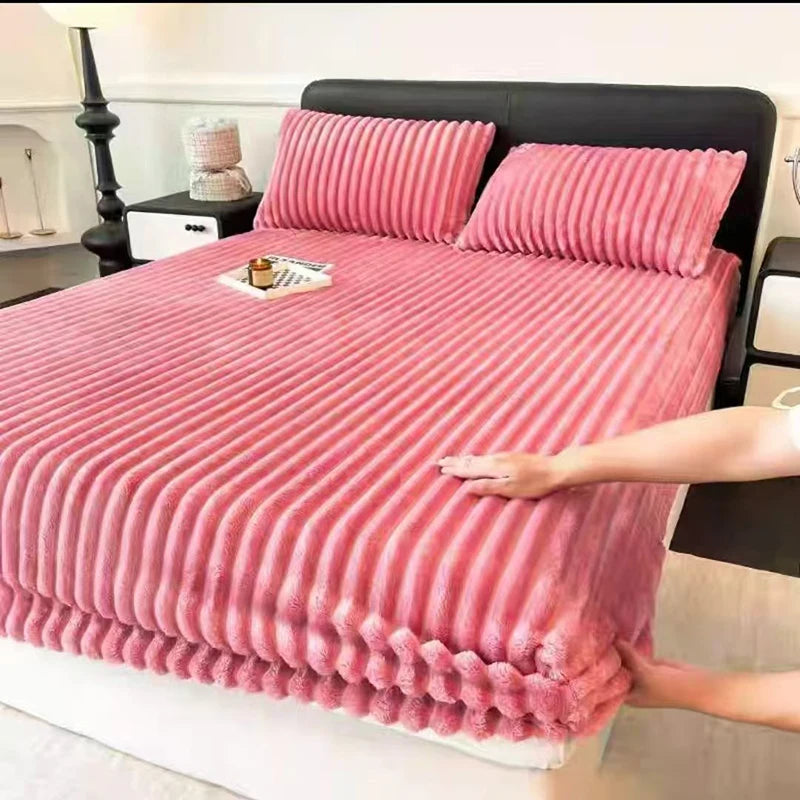 A pink knitted fitted bed sheet is laid out on a black bed with a headboard.