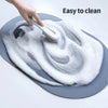 A hand is cleaning a gray bath mat with a white sponge, demonstrating its easy to clean feature.