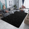 A dark black Nordic furry accent rug placed in a modern living room with a gray sofa and decor.