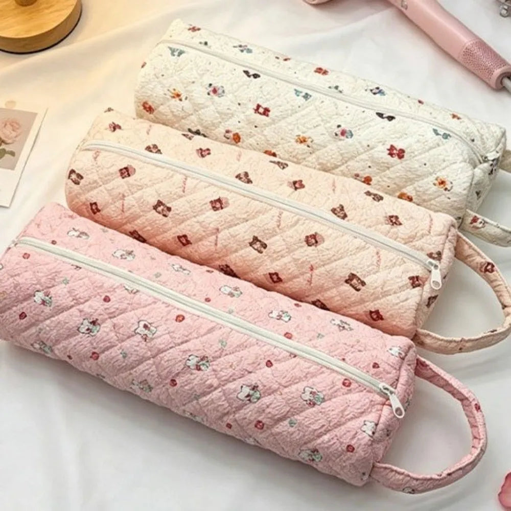 Three pink quilted cotton hair dryer storage bags lined up on a white surface.