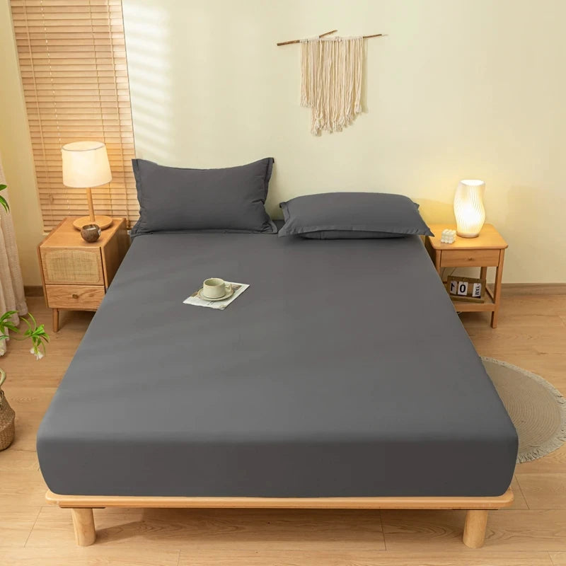 A gray fitted bed sheet set with pillowcases and a matching blanket is displayed on a wooden bed frame.