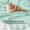 A fluffy ginger cat relaxing on a light green cotton blanket, highlighting the product's comfort and breathability.
