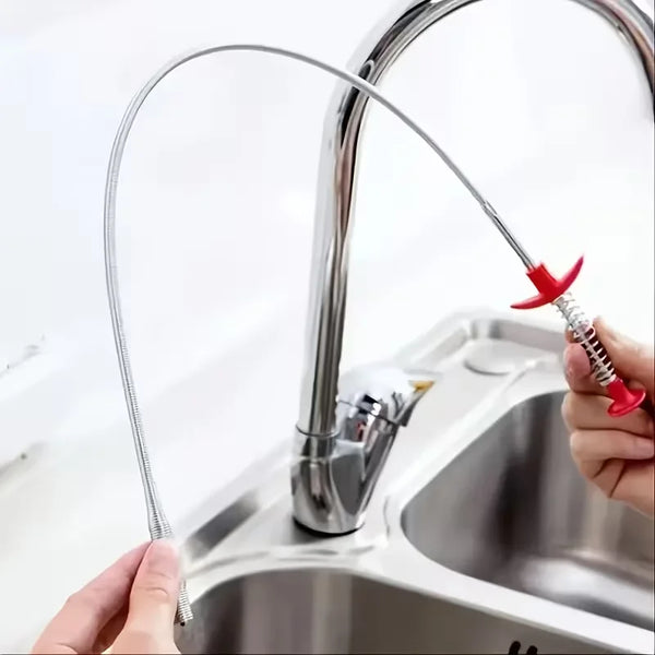 Eine Hand benutzt ein flexibles Abflussreinigungswerkzeug, um eine Küchenspüle zu reinigen.