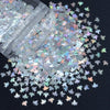 A close-up view of shiny holographic star sequins scattered on a dark surface.