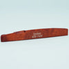 A wooden acoustic guitar bridge saddle with the name Guyker ATR-7439 engraved on it.