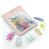 A clear plastic pouch containing colorful decorative bookmarks and paper clips