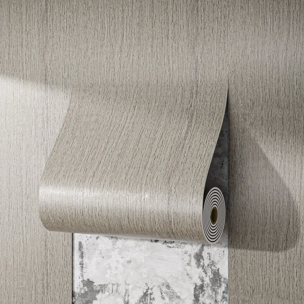 A roll of self-adhesive wood grain wall sticker with a textured surface is shown against a light gray wall.