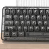 A close-up view of a black mechanical keyboard with crystal clear keycaps and RGB backlighting resting on a wooden surface.