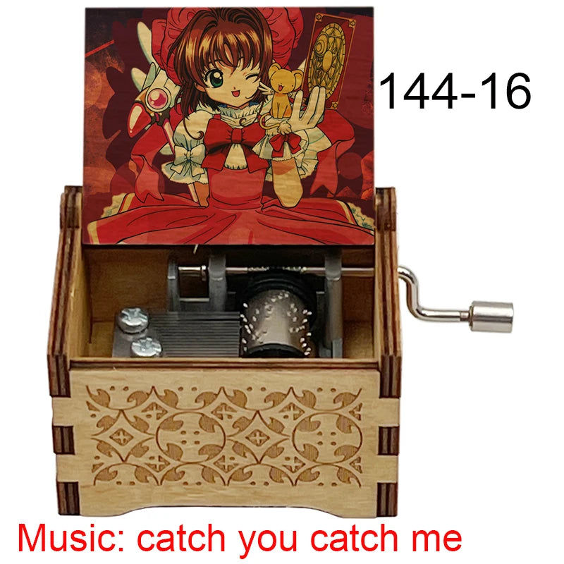 A wooden music box featuring a cardcaptor sakura theme, with an open compartment showing the mechanism and a hand crank.