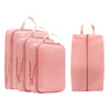A set of pink compressible packing cubes with fabric handles for travel organization.