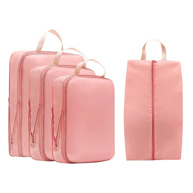 A set of pink compressible packing cubes with fabric handles for travel organization.