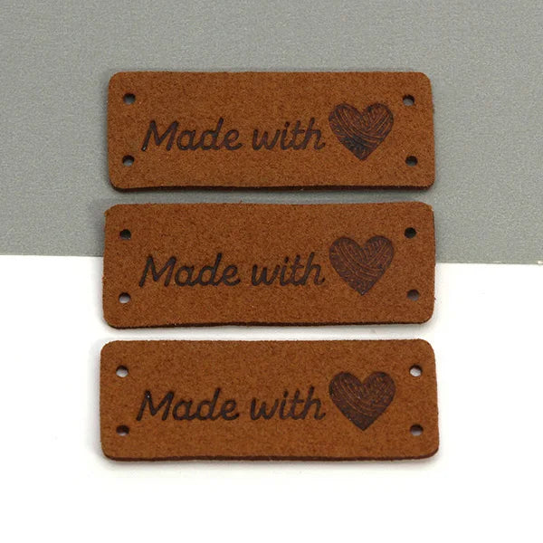 Three rectangular brown leather labels with the text Made with and a heart design.