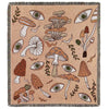 A woven throw blanket featuring a beige background with illustrations of mushrooms and eyes.