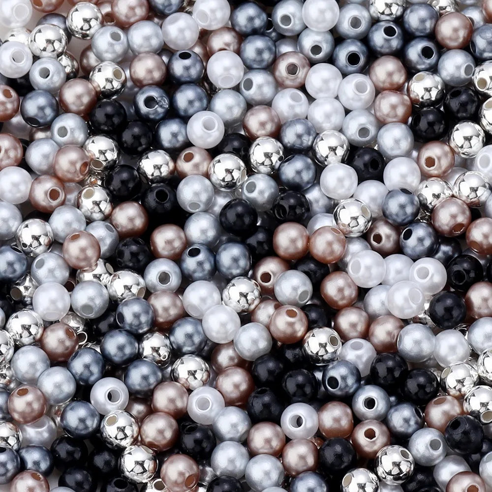 A close-up of round imitation pearl beads in various shades including white, silver, gray, black, and rose gold.