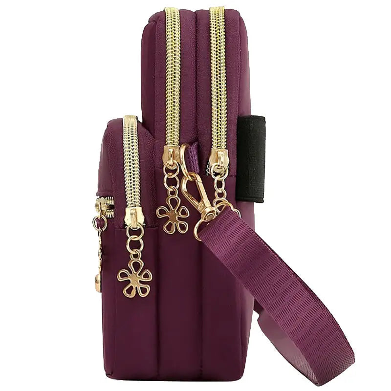 Bolso cruz impermeable de nylon morado con herrajes dorados y correa negra.