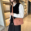 A woman wearing a black vest and skirt holds a light pink nylon crossbody bag.