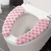 A plush pink winter toilet seat cushion cover is shown inside a white toilet bowl.
