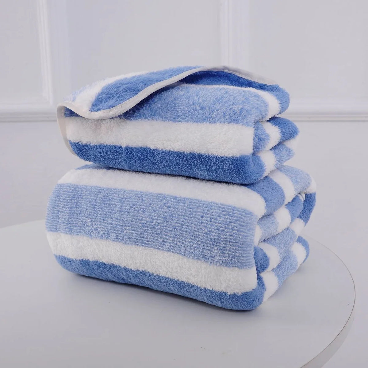 A stack of blue and white striped microfiber towels for bath and face use.