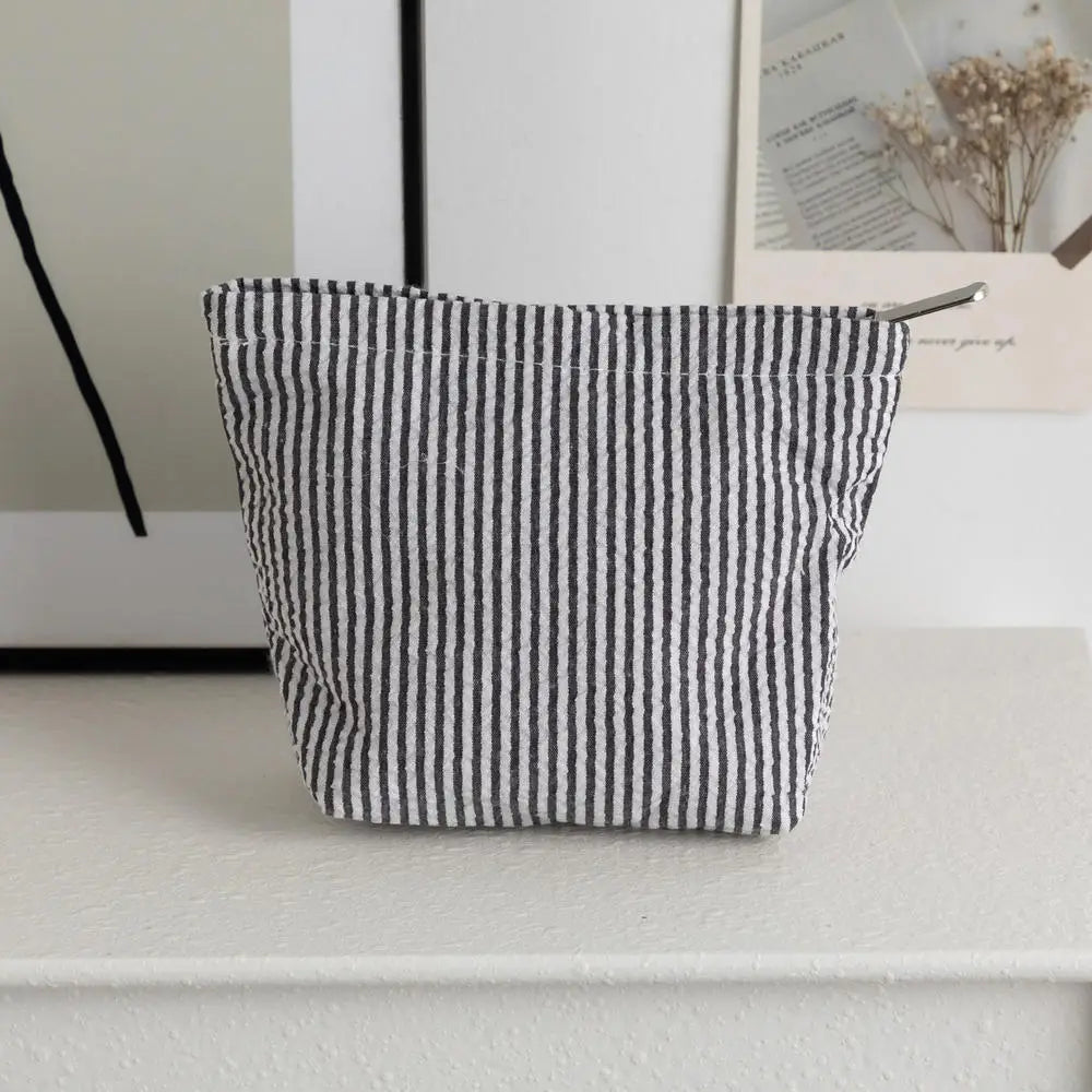 Pochette en crochet à rayures noires et blanches posée sur une surface blanche.