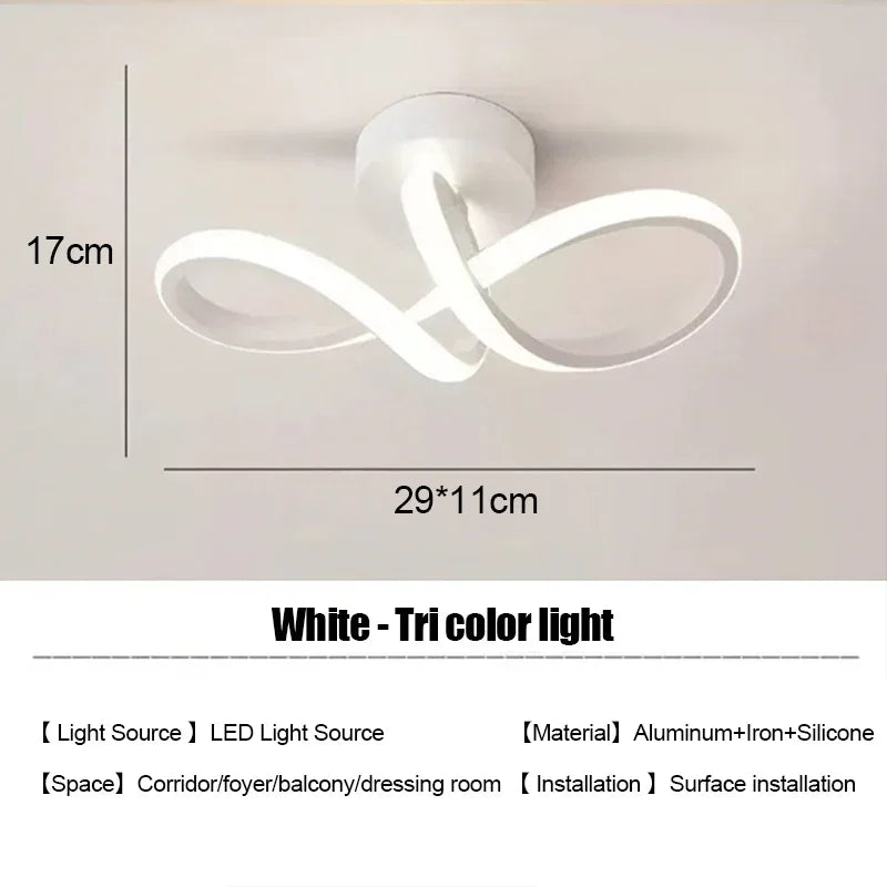 White tri-color LED light fixture with a swirling design mounted on a wall.