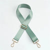 A light sage green adjustable nylon bag strap with a gold buckle.