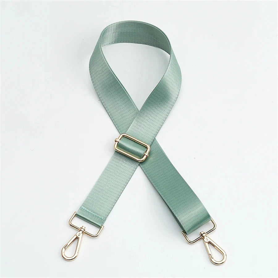 A light sage green adjustable nylon bag strap with a gold buckle.