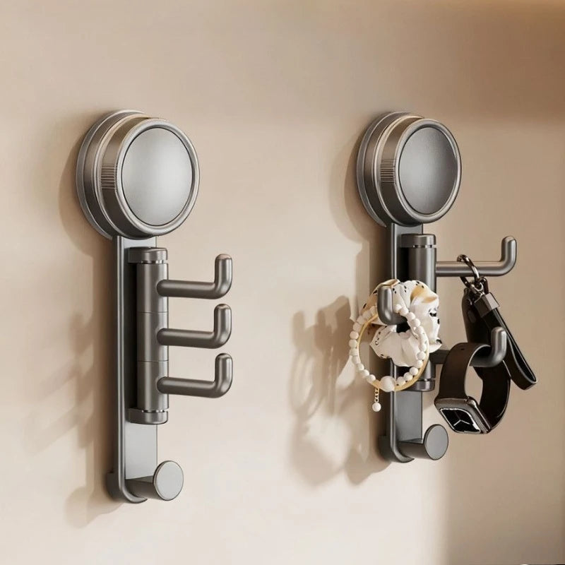 A pair of modern, silver suction cup hooks with a rotating head mounted on a beige wall.